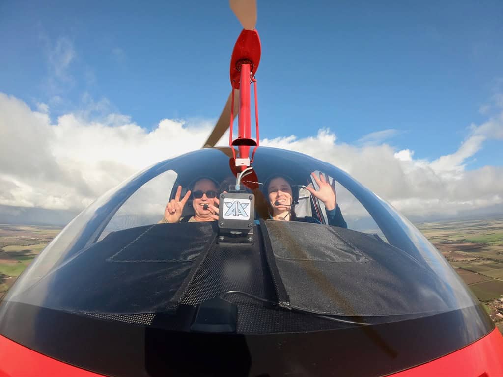 People waving as they are flying an enclosed gyro